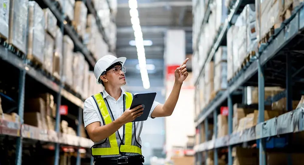 An employee using a tablet to manage stock levels and shipments, showcasing the user-friendly features of WMS software. 